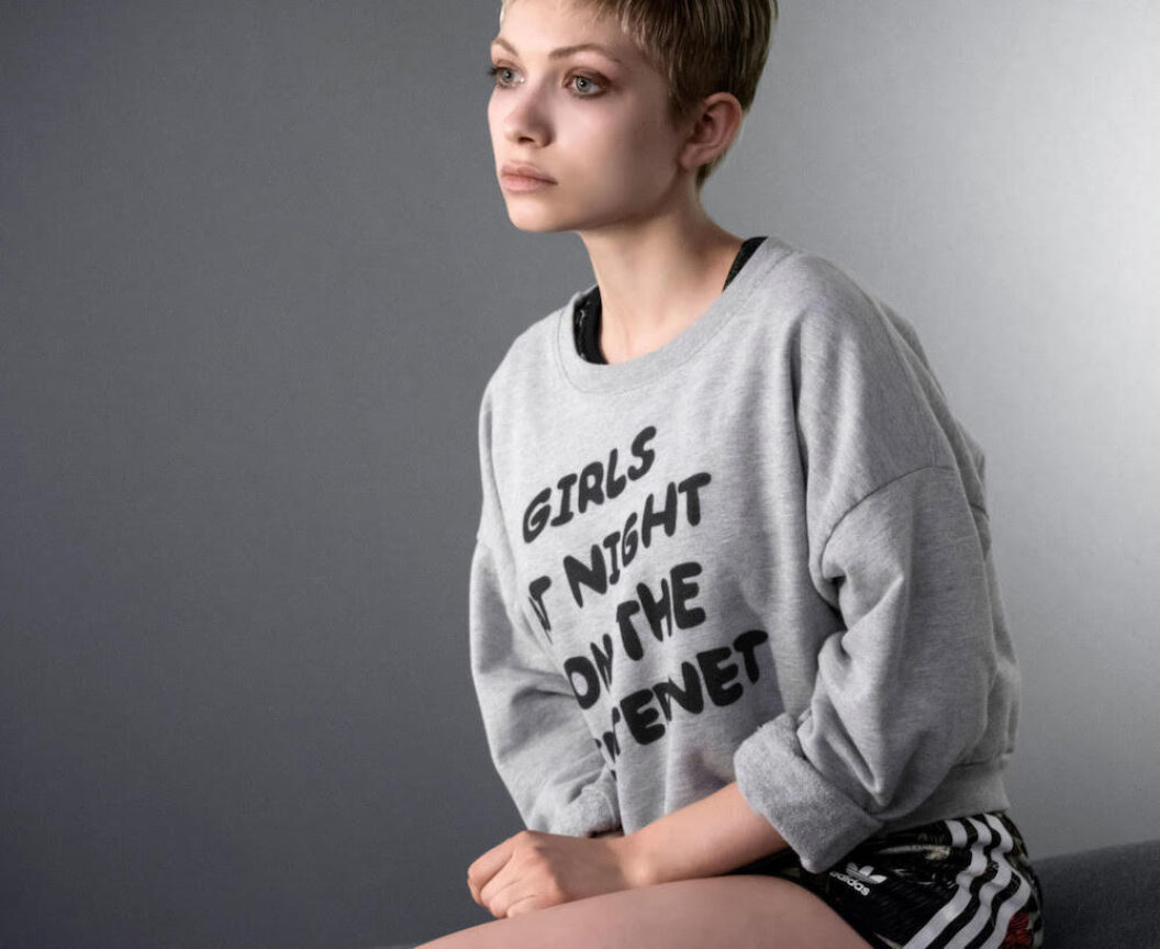 Person with light eyes and short blondish hair sitting and looking in the distance with the words